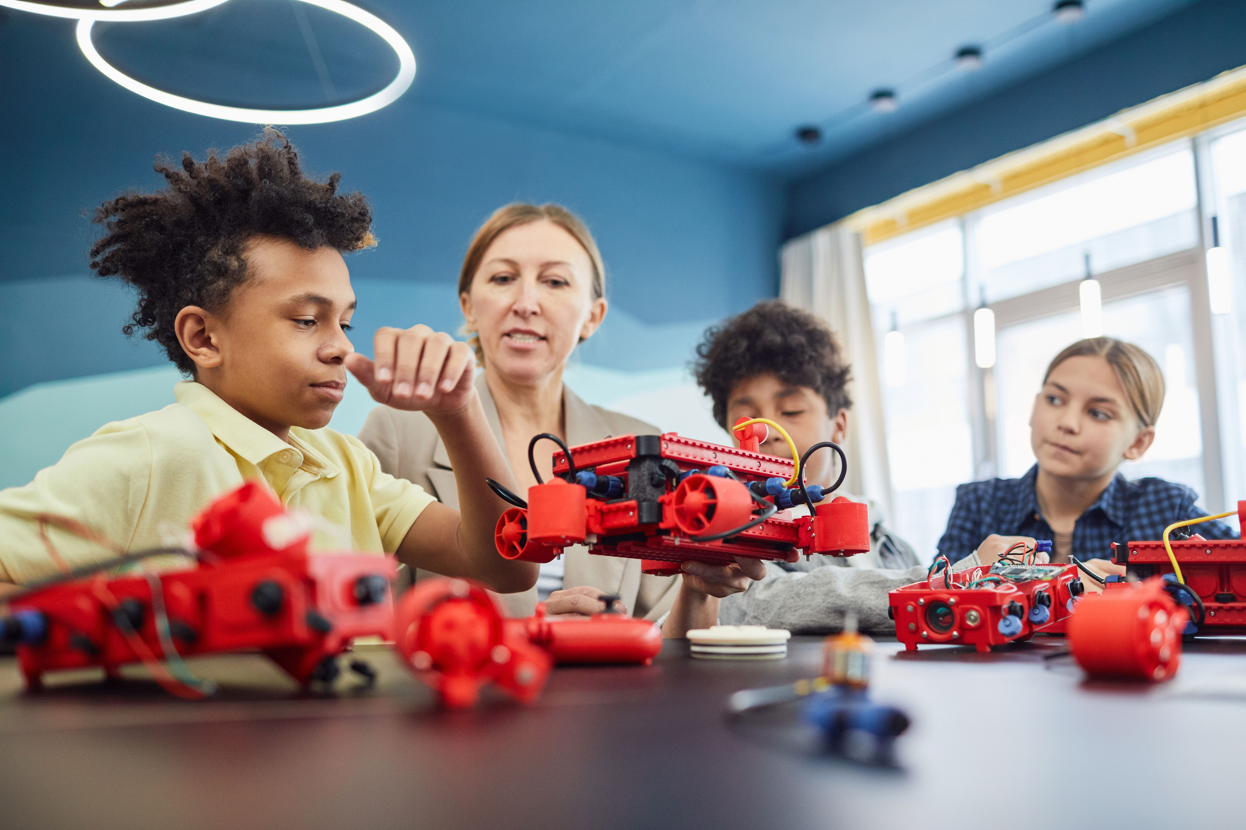 Children doing robotics at after school club with teacher - Ofsted looks for activities that support development and wellbeing in out of school provision